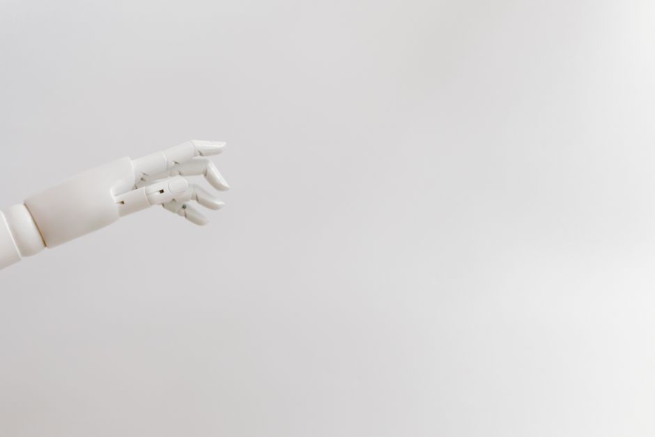 Minimalist image of a robotic hand reaching out on a white background.. Photo by Tara Winstead on Pexels