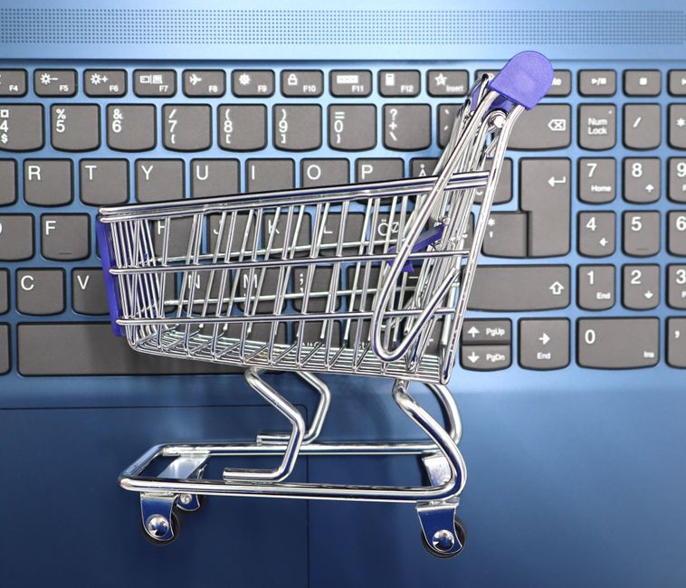 A miniature shopping cart placed on a laptop keyboard symbolizing online shopping and e-commerce.. Photo by SiljeAO - on Pexels