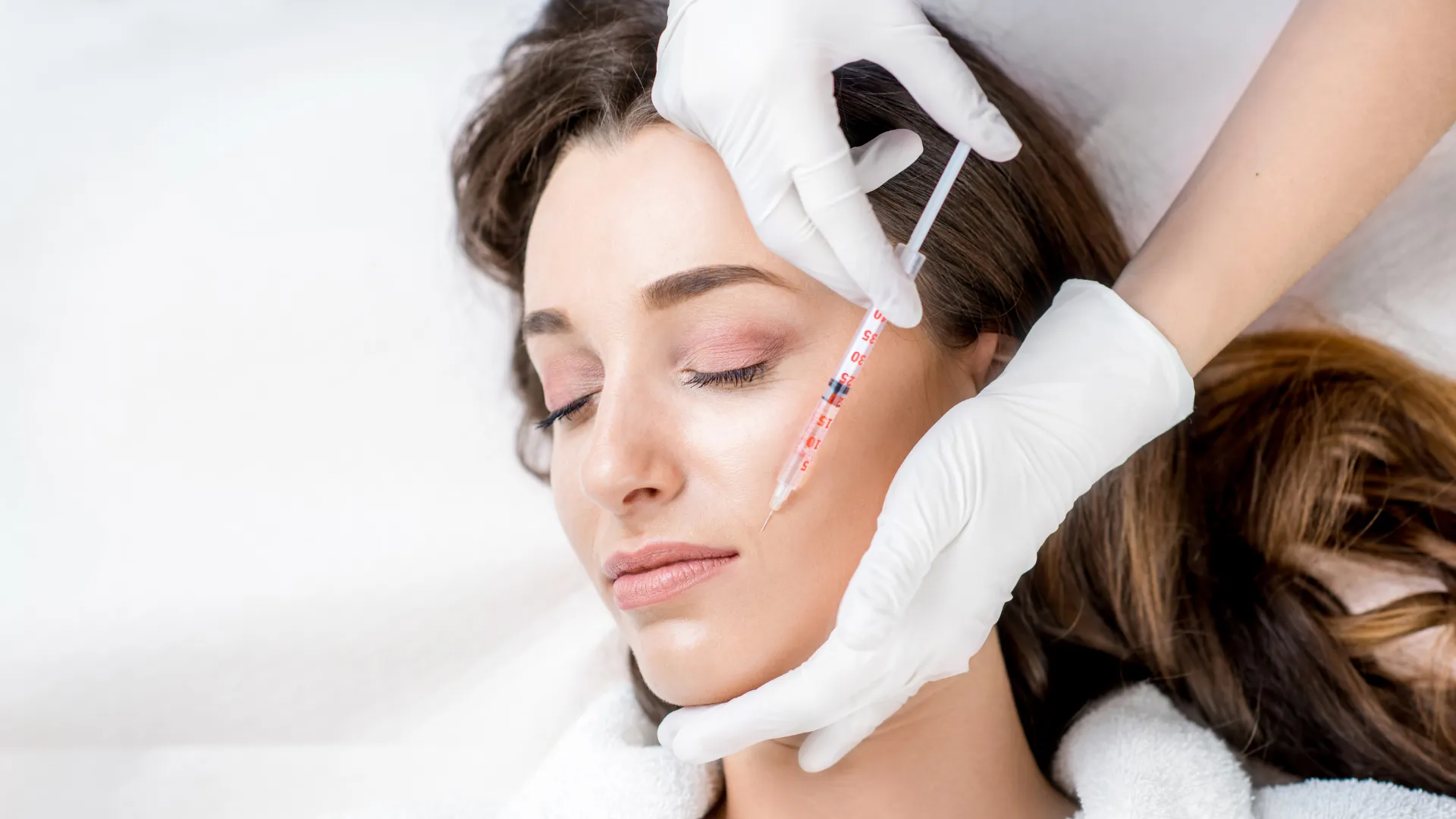 Injection esthétique sur le visage d'une femme avec une seringue pratiquée par un médecin
