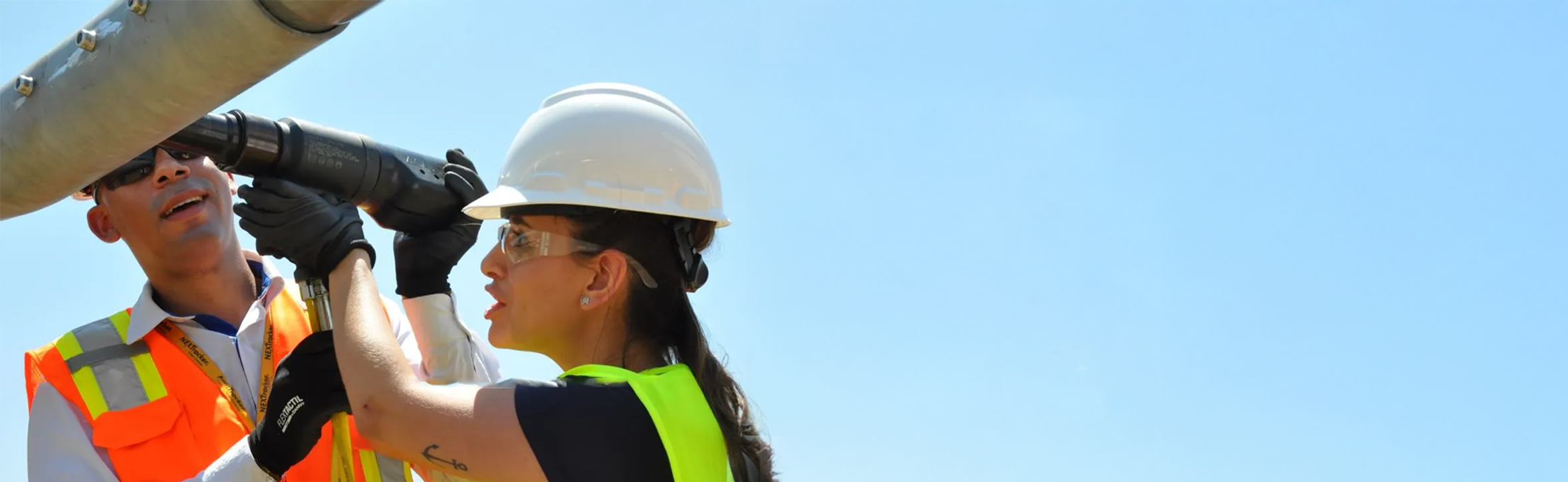A woman and man in safety gear fixing a wind turbine