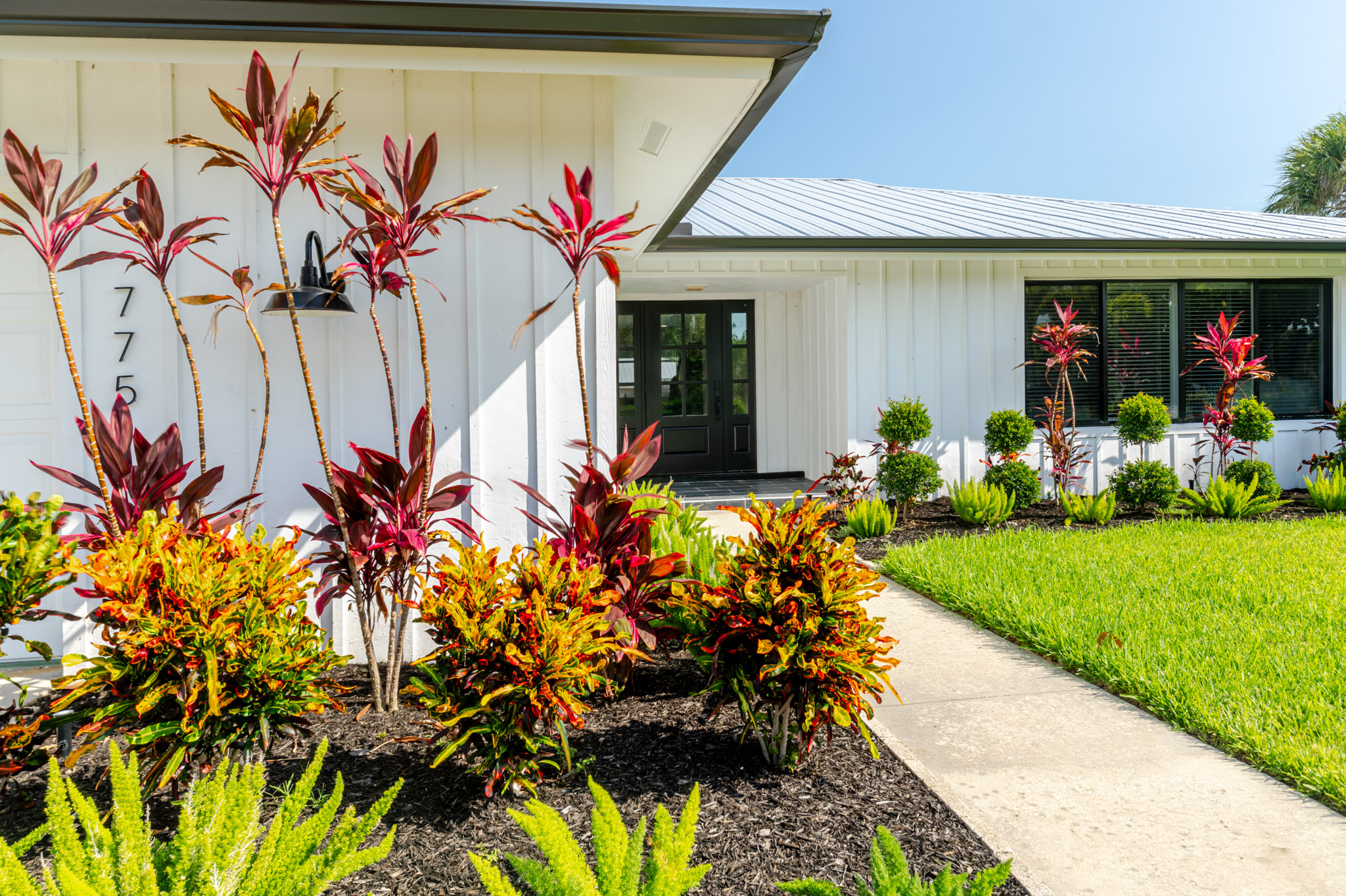 Exterior of Sanibel Coastal Cottage vacation rental on Sanibel Island, featuring lush landscaping, palm trees, and a peaceful East End location.