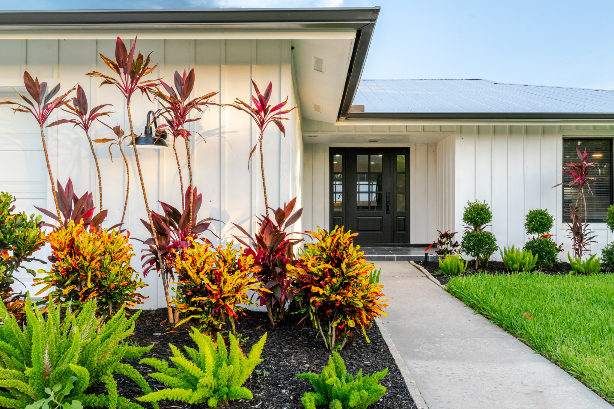 View of the front door of the coastal cottage featuring garden and landscaping
