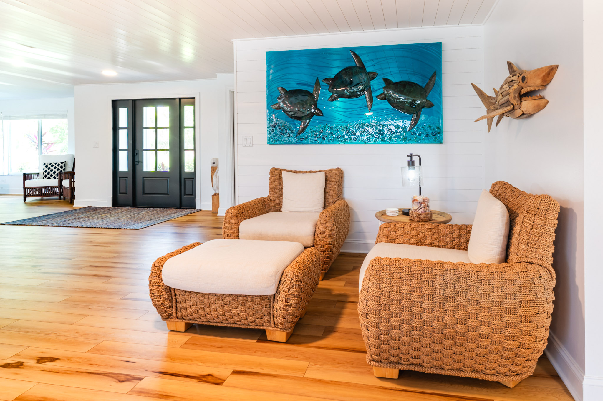 Pair of woven rattan chairs beneath bold nautical wall art.