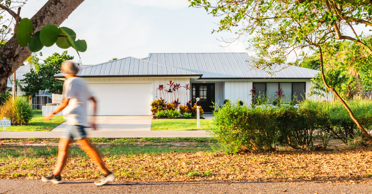 Morning walker strolls on the walking path in front of the coastal cottage in the morning light. 