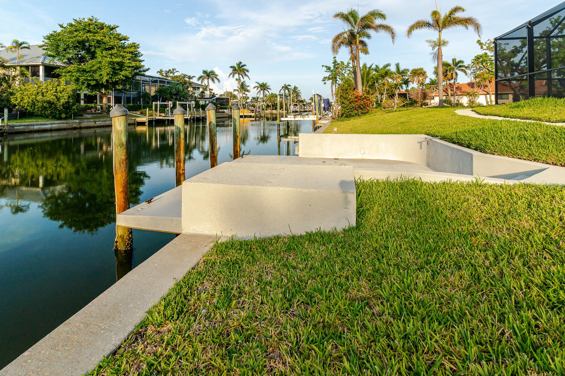 View from grassy lawn to private canal dock with concrete seawall.