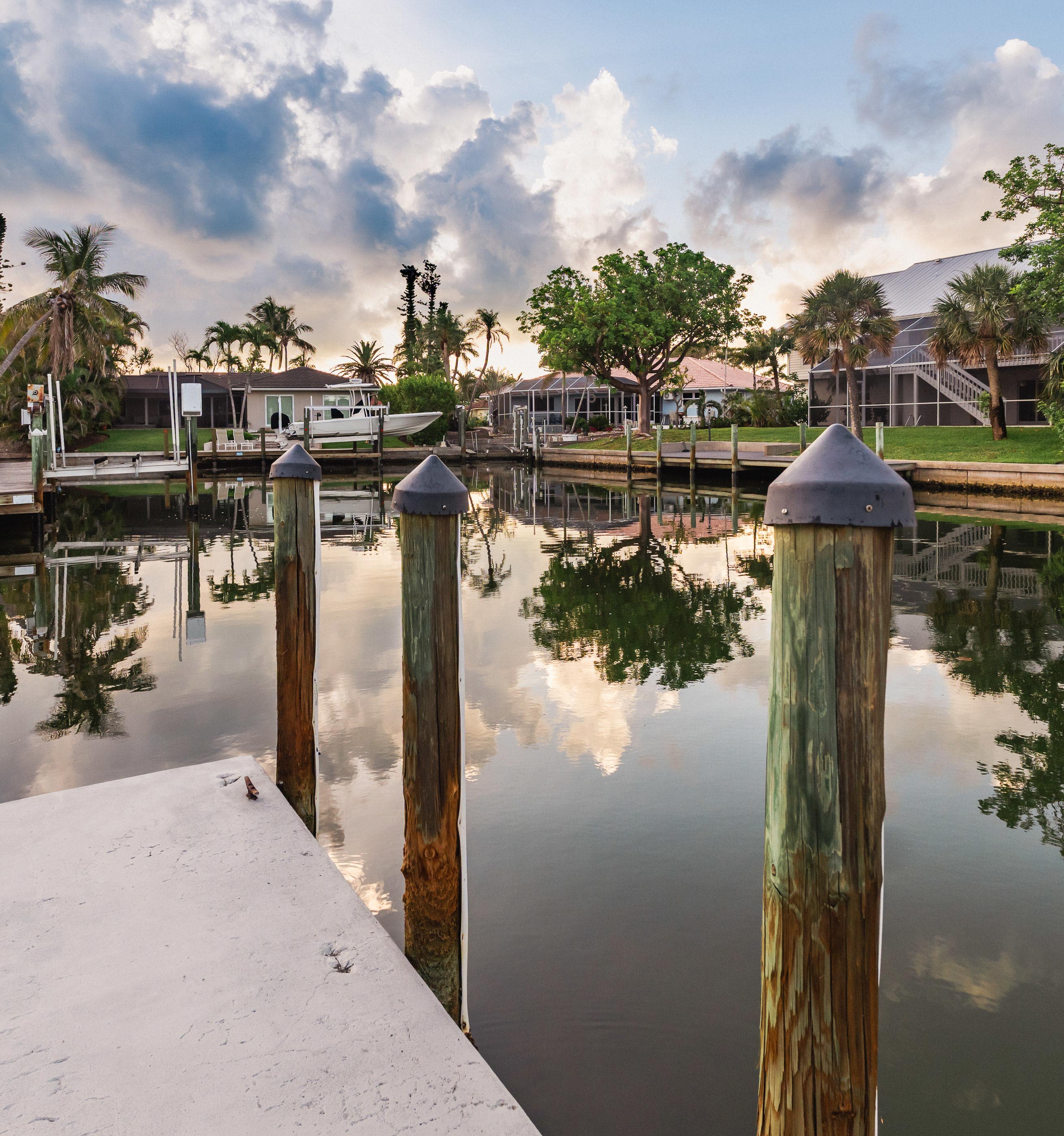 Close-up view of dock pilings on a calm Sanibel canal at golden hour.
