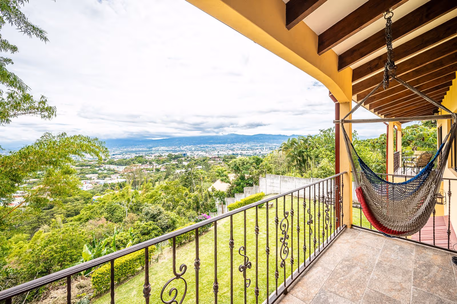 Second-floor balcony of Escazú luxury estate with breathtaking panoramic city views, cozy enough for a garden table for two—perfect for morning coffee or sunset conversations. Adjacent to two bedrooms.