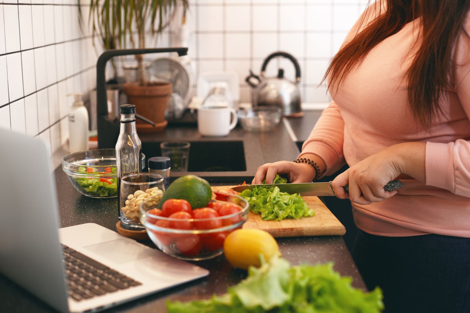 A woman cutting vegetables on a cutting board.