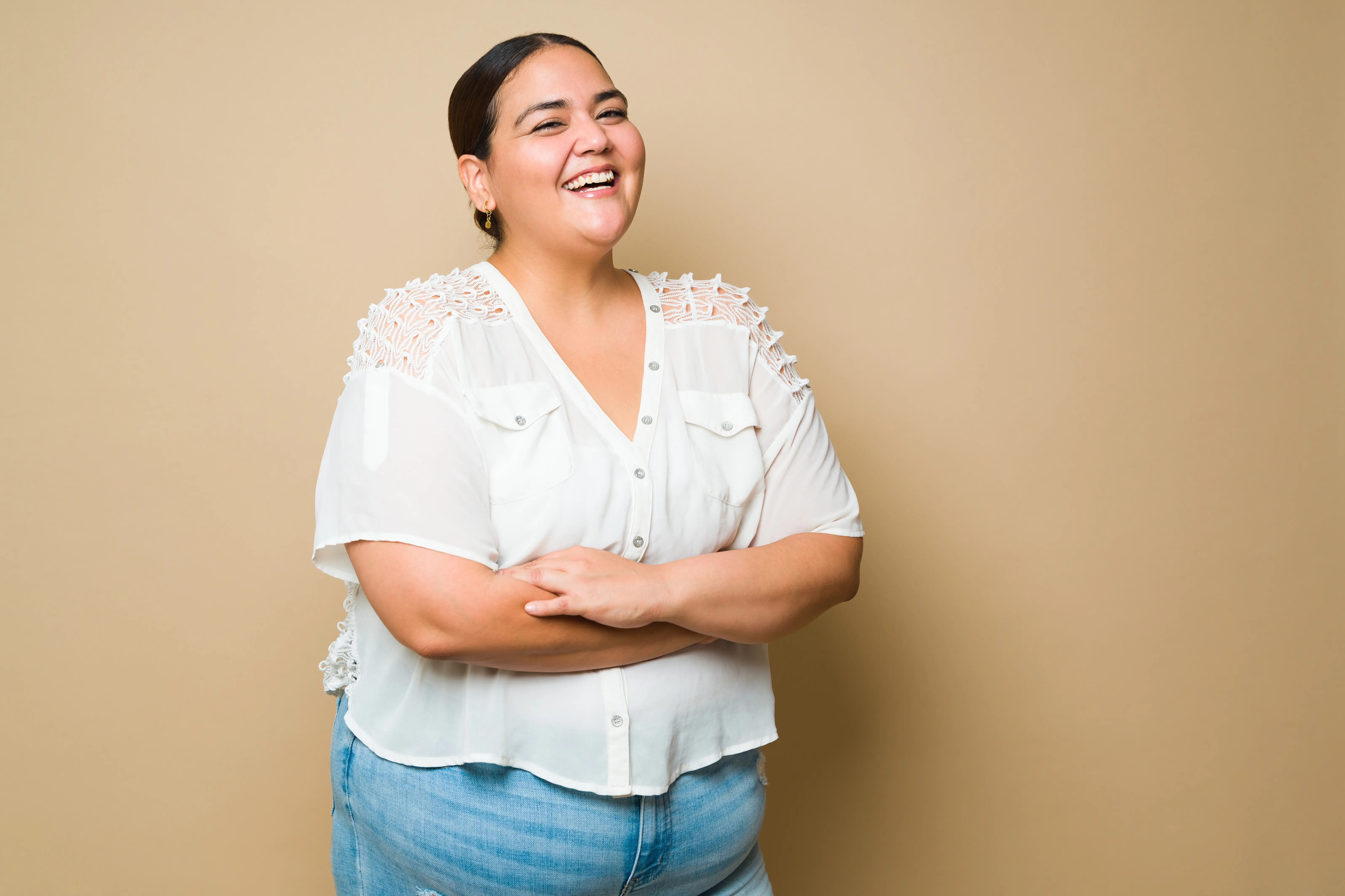 A woman standing with her arms crossed and smiling.