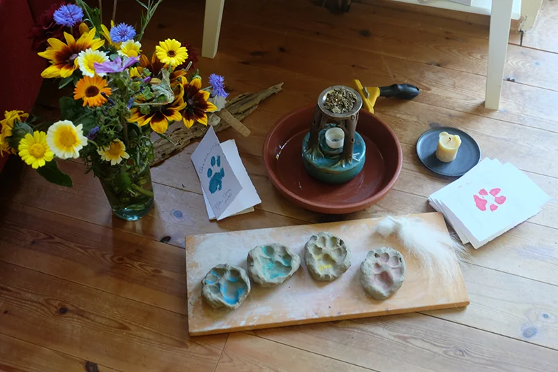 Pfotenabdrückel aus Ton neben einem Blumenstrauß