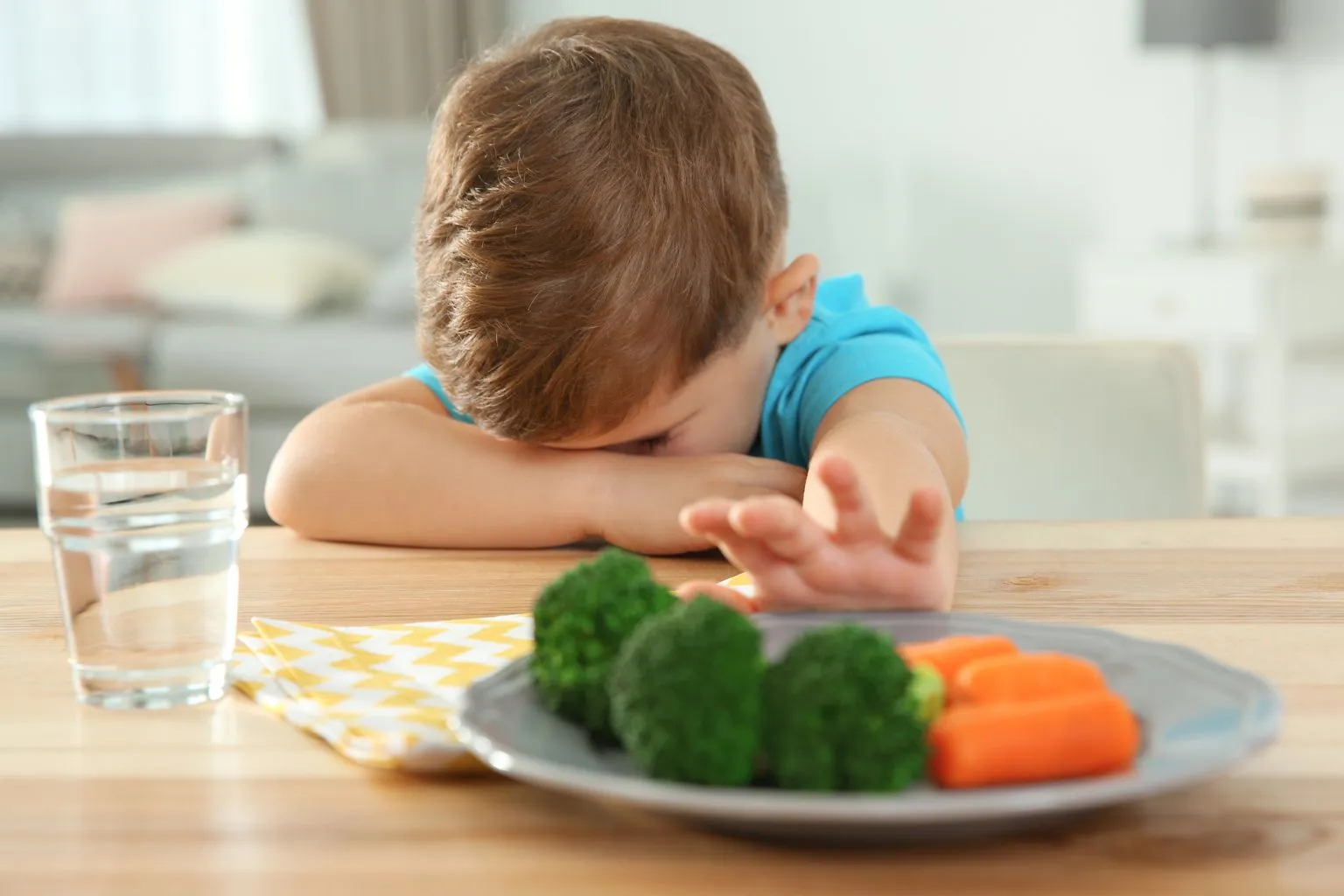 Toddler at dinner table refusing vegetables, illustrating picky eating challenges