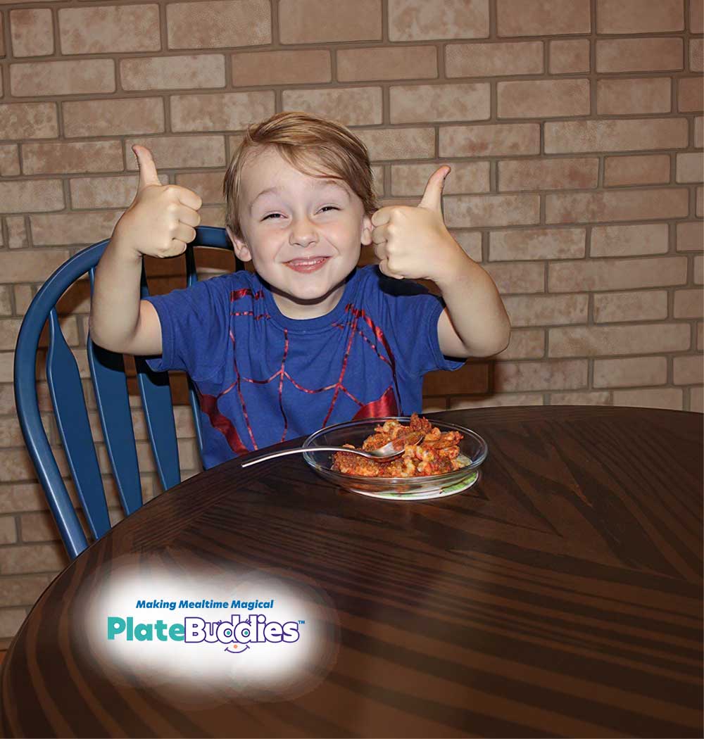 Smiling child giving thumbs up at the dinner table with a Plate Buddies meal.