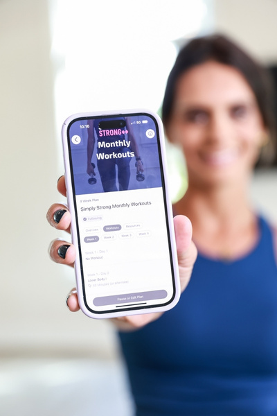 Tami Smith, holding the Simply Strong App and showing the women's strength training program.