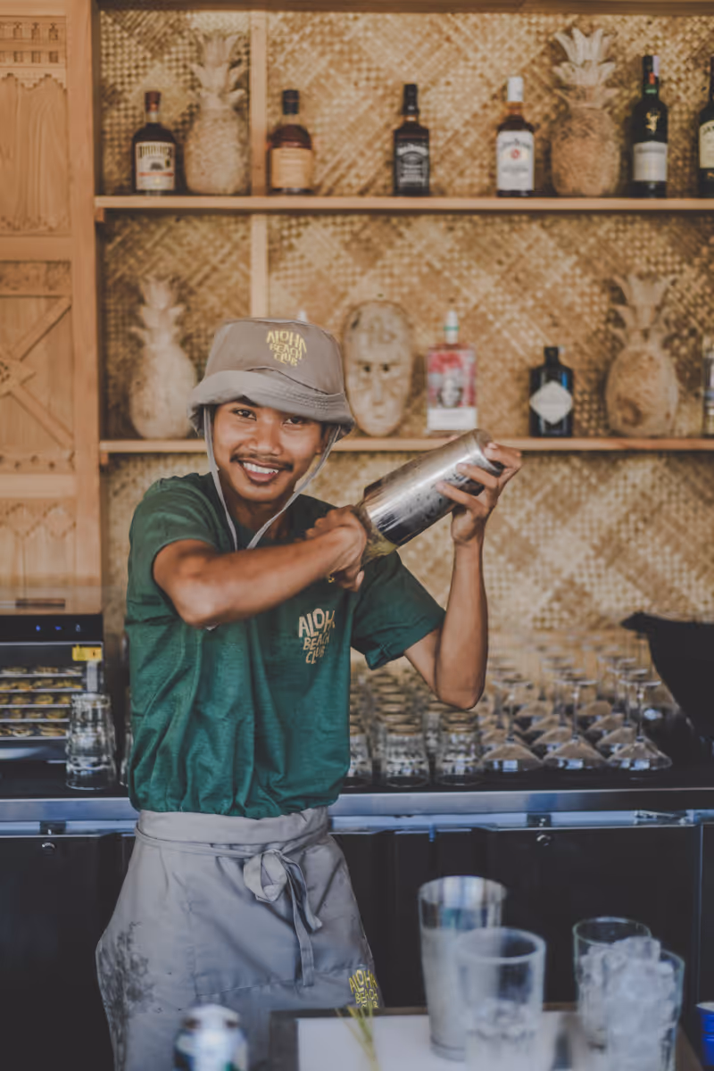 Friendly bartender at Aloha Beach Club shaking a cocktail behind the bar.