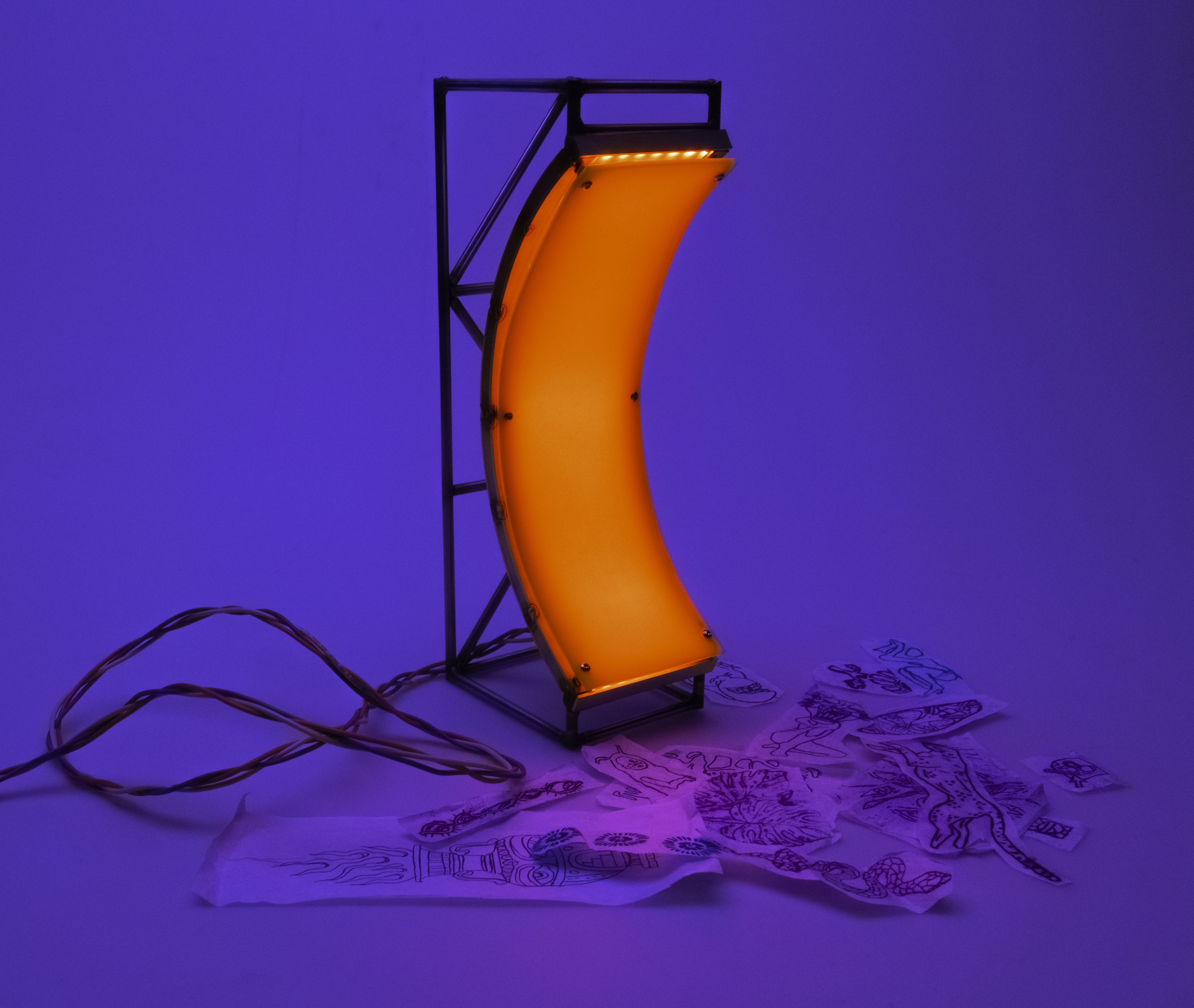 Curved orange neon light mounted on a black metal frame with tangled red cords, surrounded by scattered tattoo flash designs on paper against a blue background.