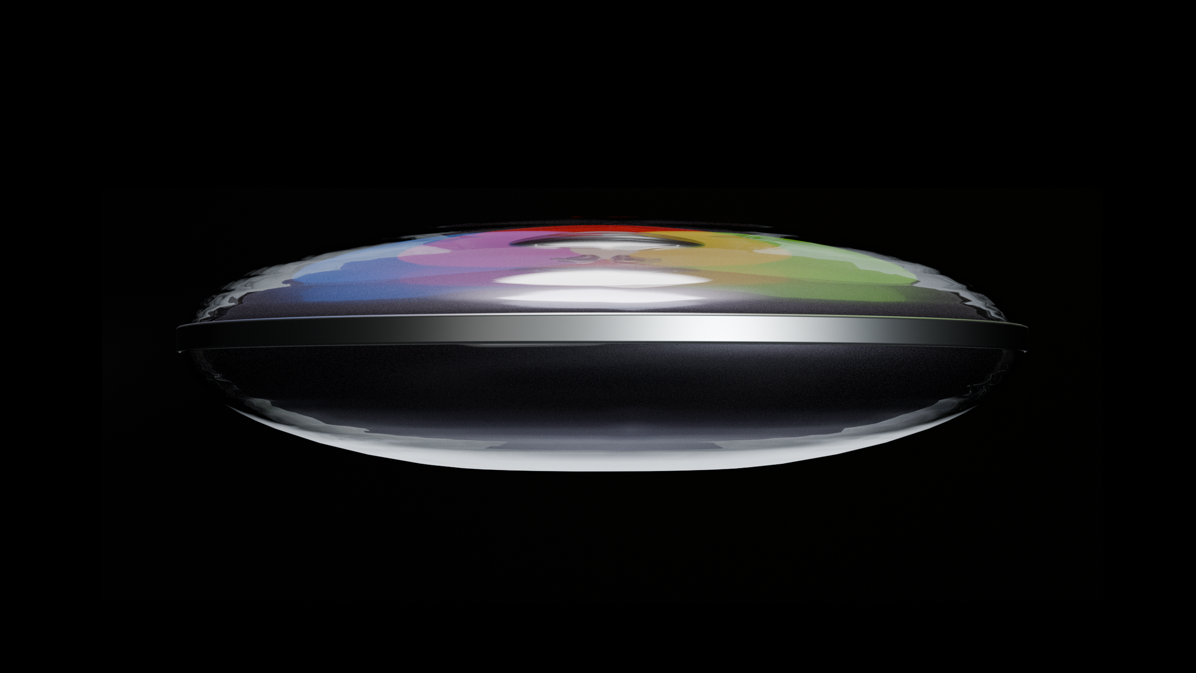 Close-up side view of a translucent, rounded device with a colorful, textured surface and a metallic band around the middle, set against a black background.
