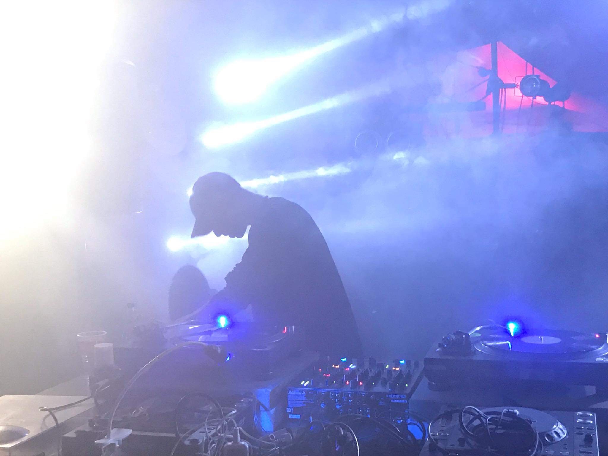 Deep in the fog—turntables, strobes, and silhouette. A cinematic vinyl session in motion.