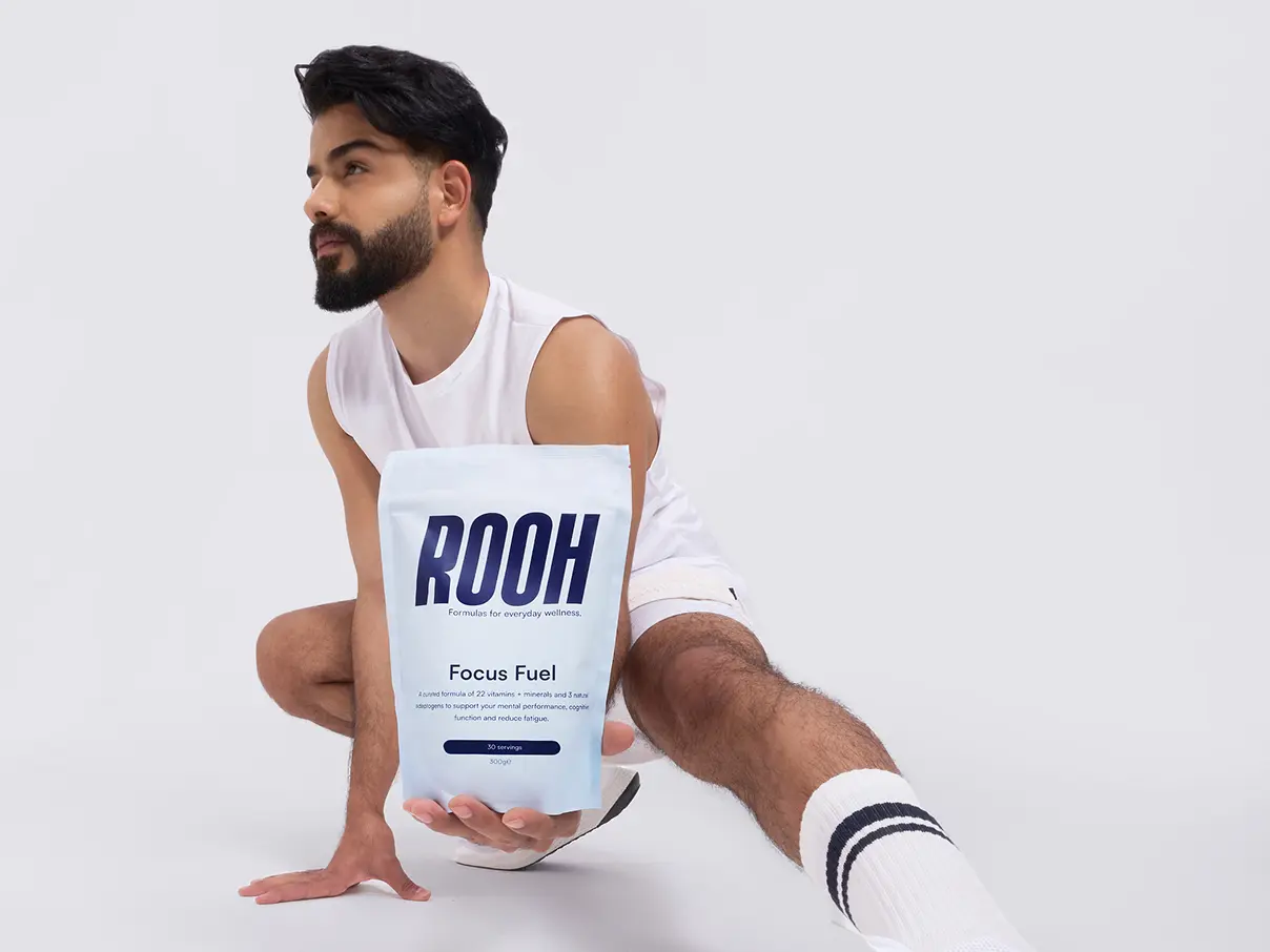 Male model wearing athletic clothing, posing for the camera and holding a ROOH formula bag.