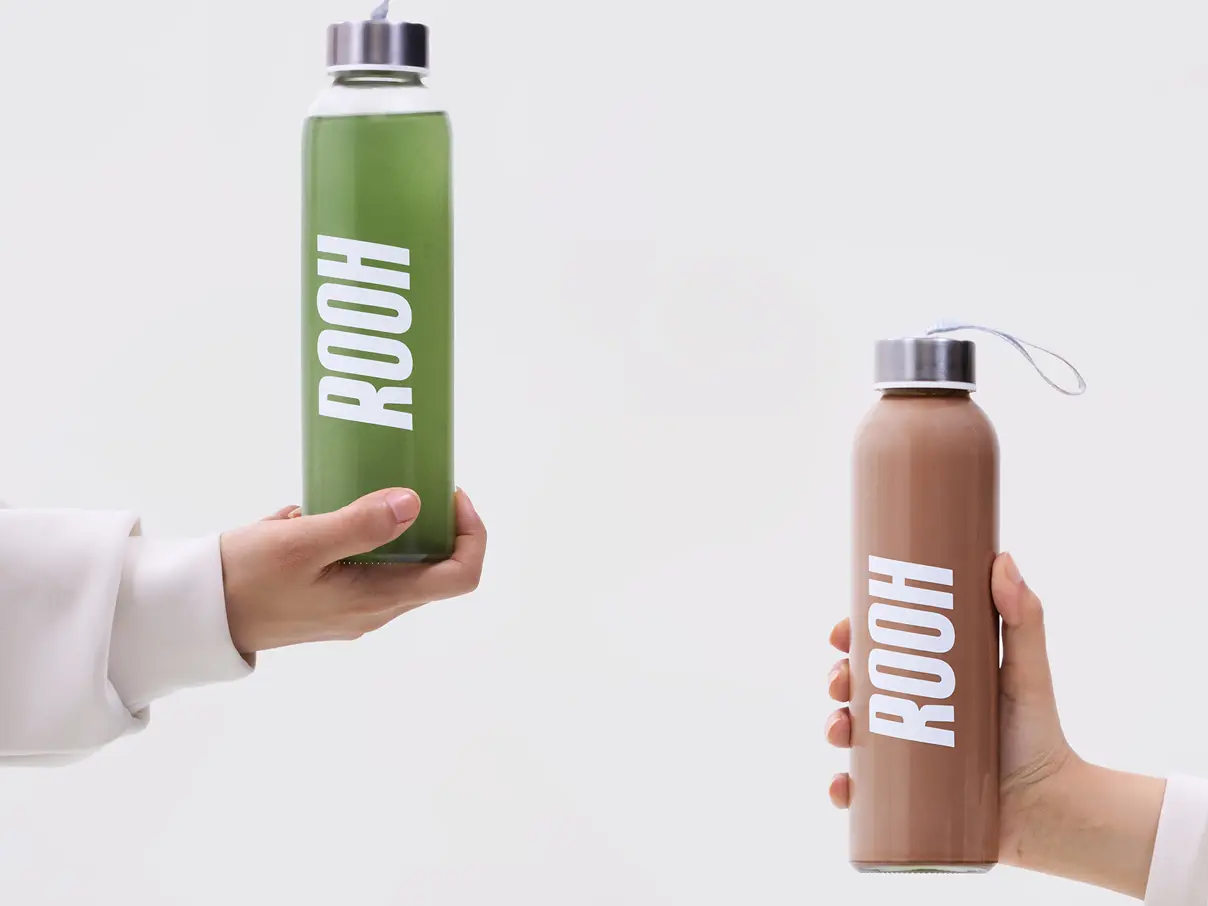 Product shot of two hands, each holding a ROOH bottle.