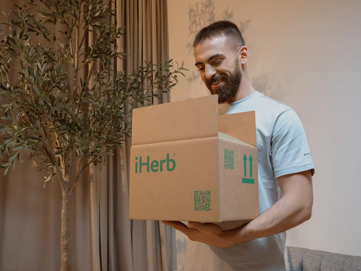 Man holding a box from iHerb.