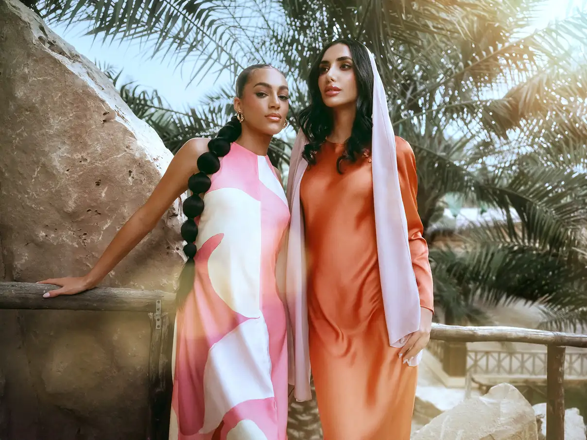 Two female models standing outdoors.