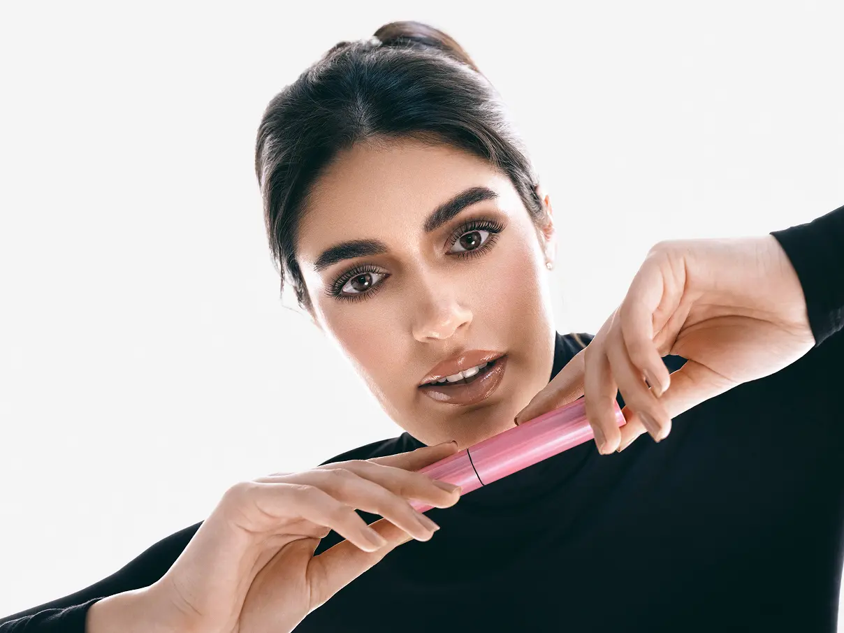 Female model, holding Asteri makeup tube.