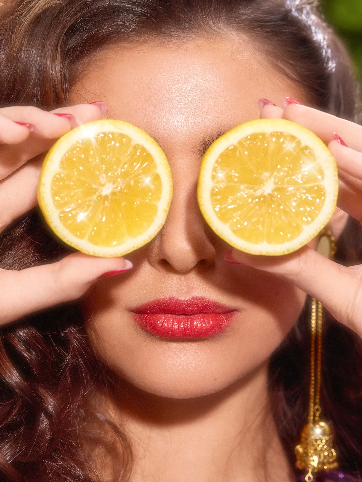 Closeup of a female model holding 2 lemon pieces in front of her eyes