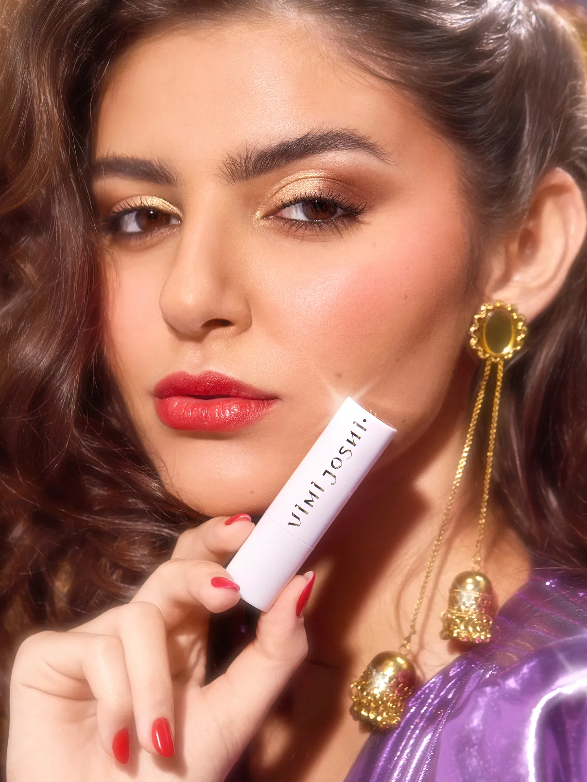 Closeup of a female model holding a makeup tube close to her face