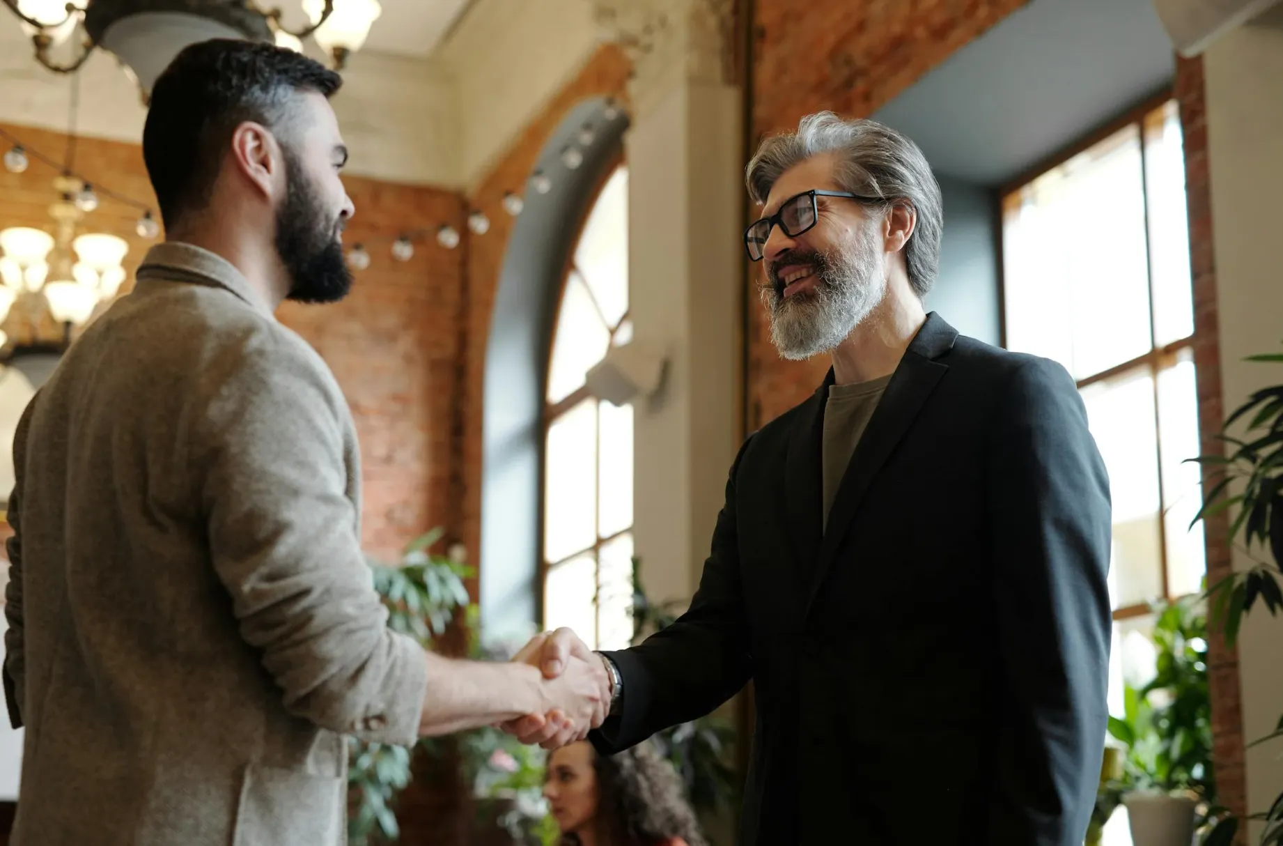 An executive coach shaking his client's hand in an office building