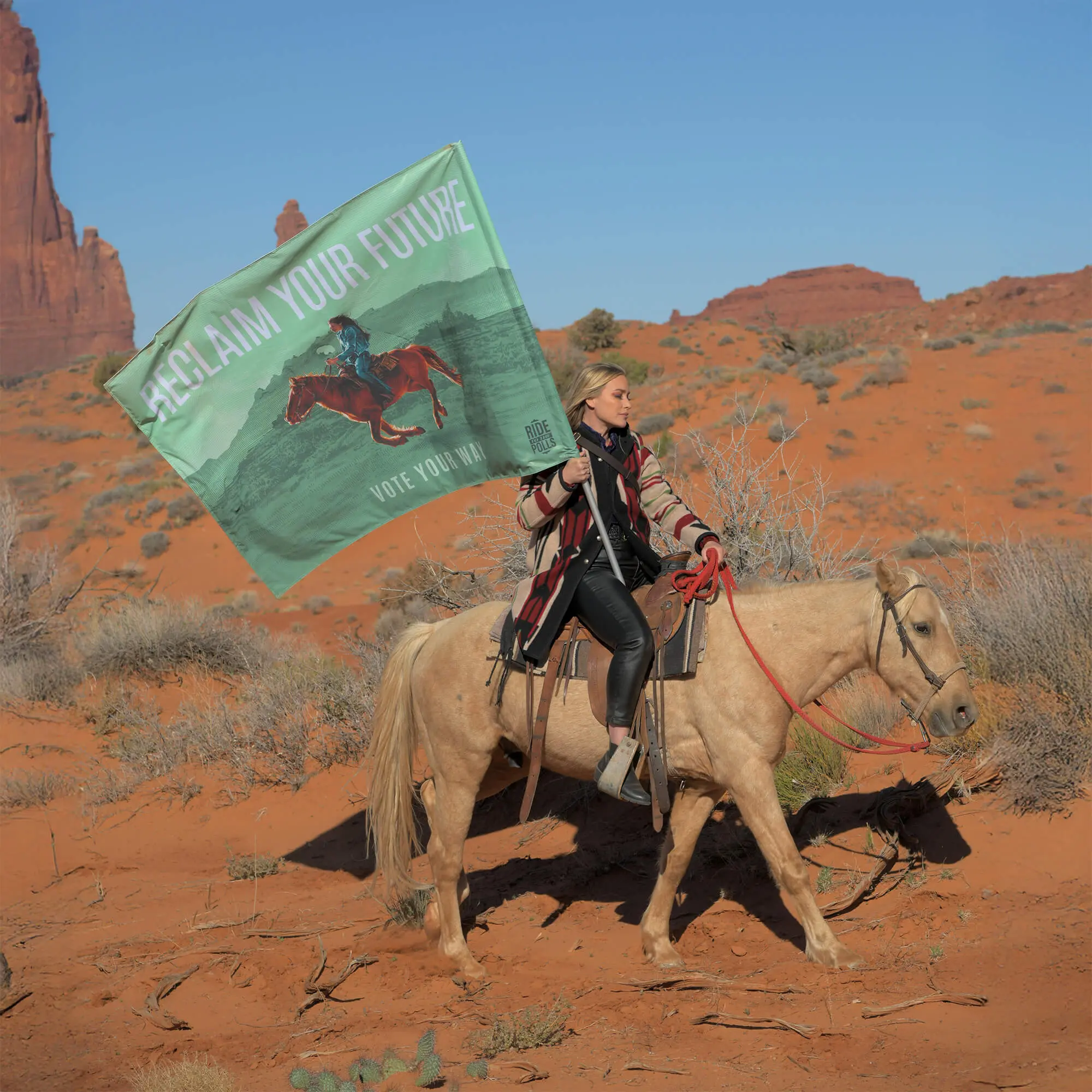 Actress Piper Perabo on horseback holding green 'Reclaim Your Future' flag in desert landscape with red rock formations for Ride to the Polls voting campaign