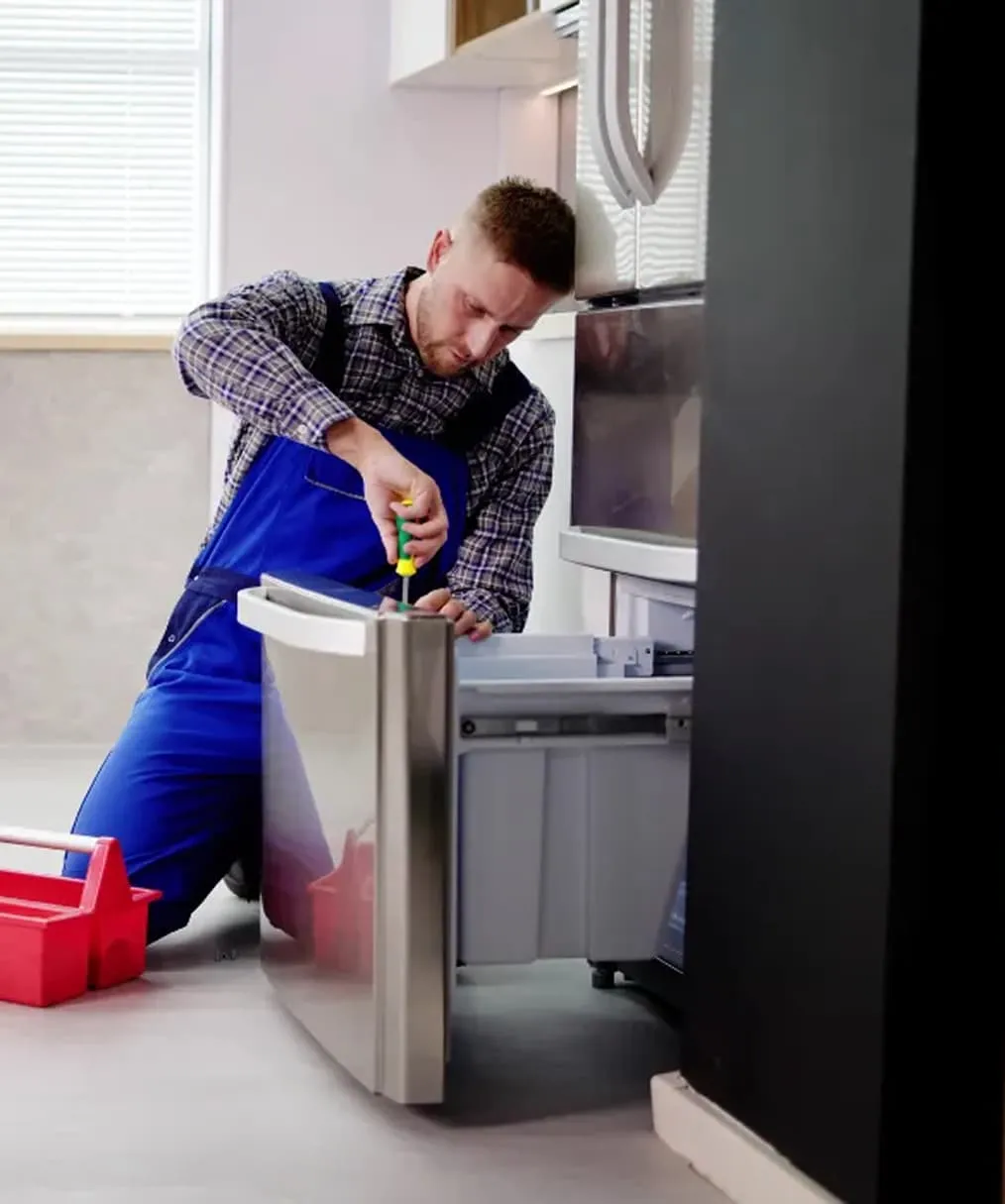 Technician performing refrigerator drawer repair in a modern kitchen in La Jolla, California.