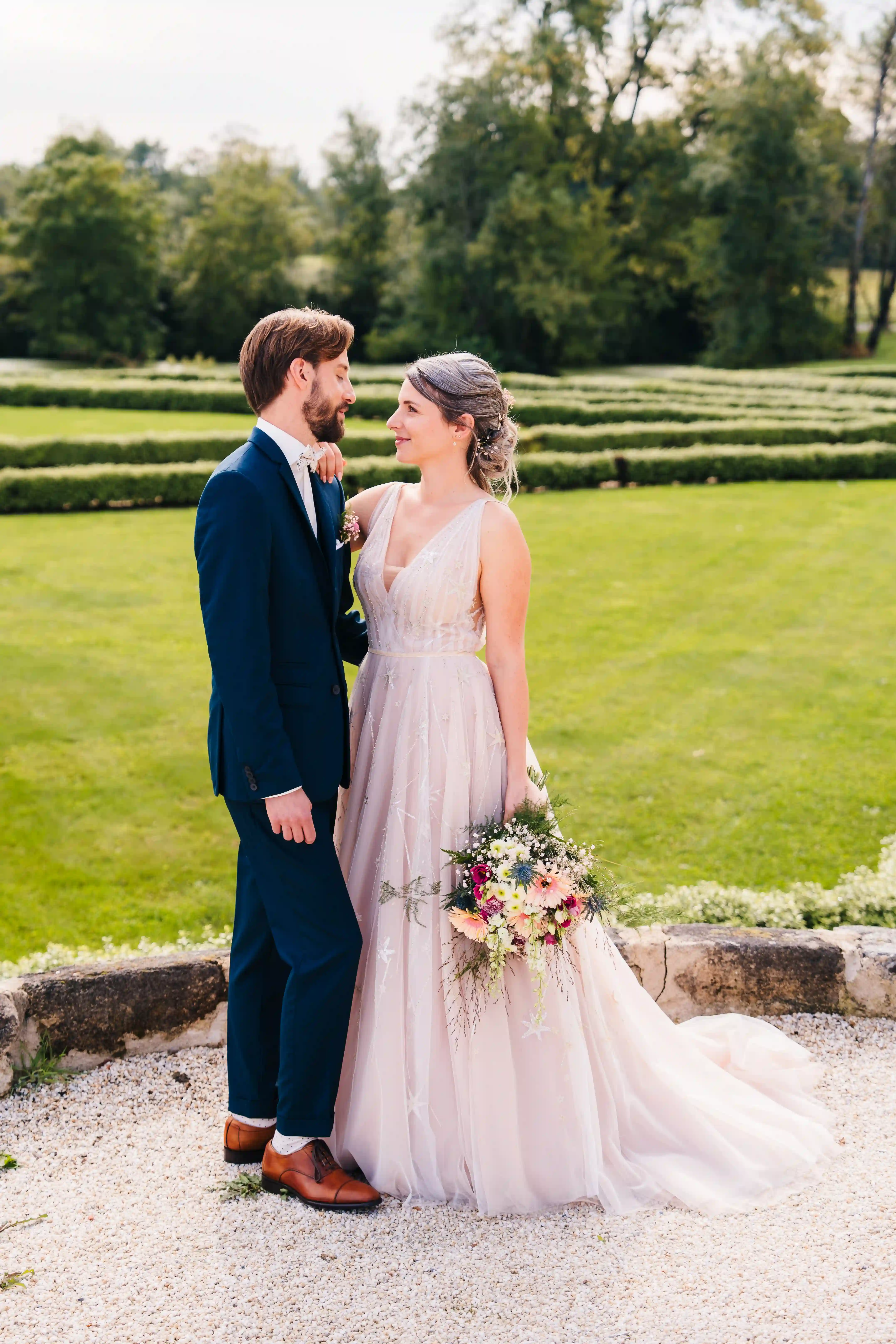 Vidéo de mariage d’un couple de jeunes mariés dans un domaine élégant, prise de vue naturelle en extérieur, moment complice capté par un vidéaste de mariage professionnel.