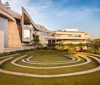 Modern building with a unique curved design and circular stepped grass amphitheater in front.