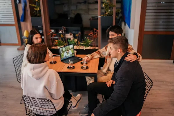 Small group meeting around laptop in modern office Beyond Border