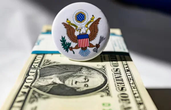 U.S. emblem pin on stack of dollar bills Beyond Border