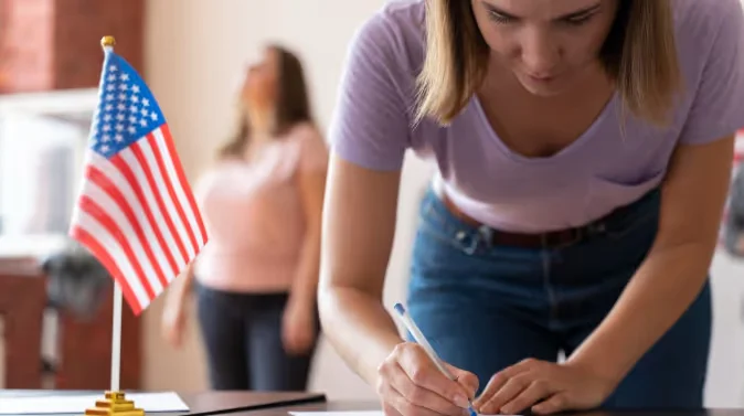 Person signing document beside small American flag Beyond Border