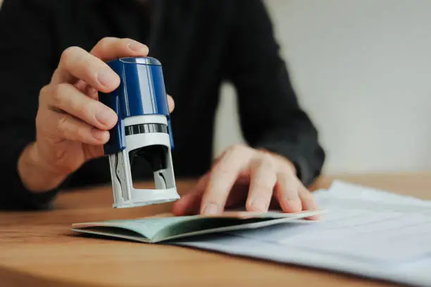 Hand stamping passport on desk Beyond Border
