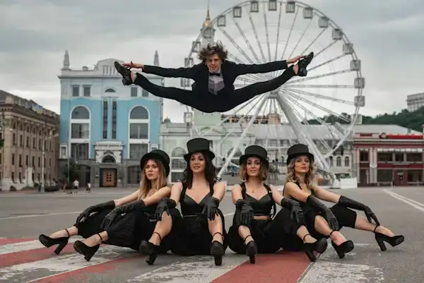 Dancer performing a split jump above a group in a city square. Beyond Border.