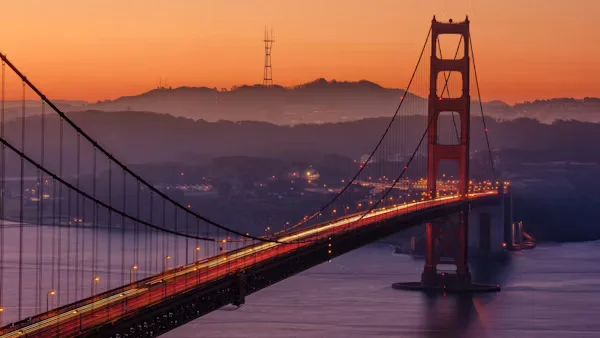 Golden Gate Bridge at sunset with city lights and foggy hills in the background. Beyond Border.