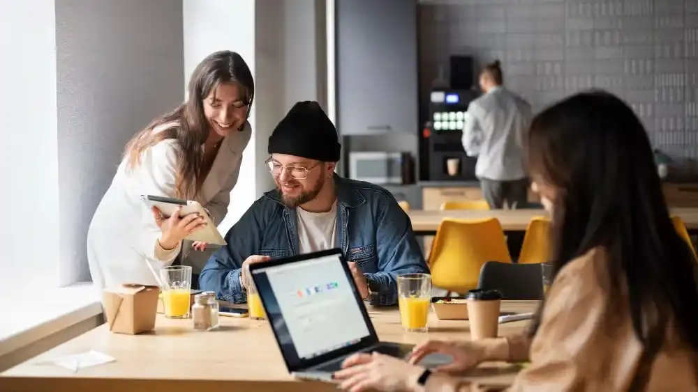 Team collaborating with laptops and tablet in a modern office space. Beyond Border.