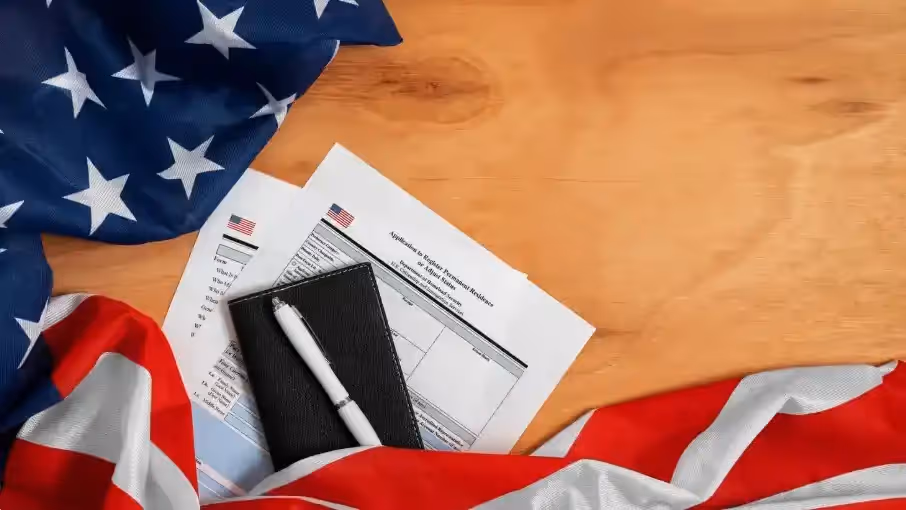 U.S. flag with documents, notebook, and pen on a wooden table. Beyond Border.