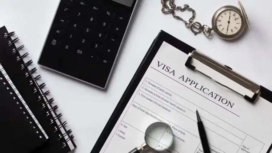 Visa application form with calculator, notebook, and magnifying glass. Beyond Border.