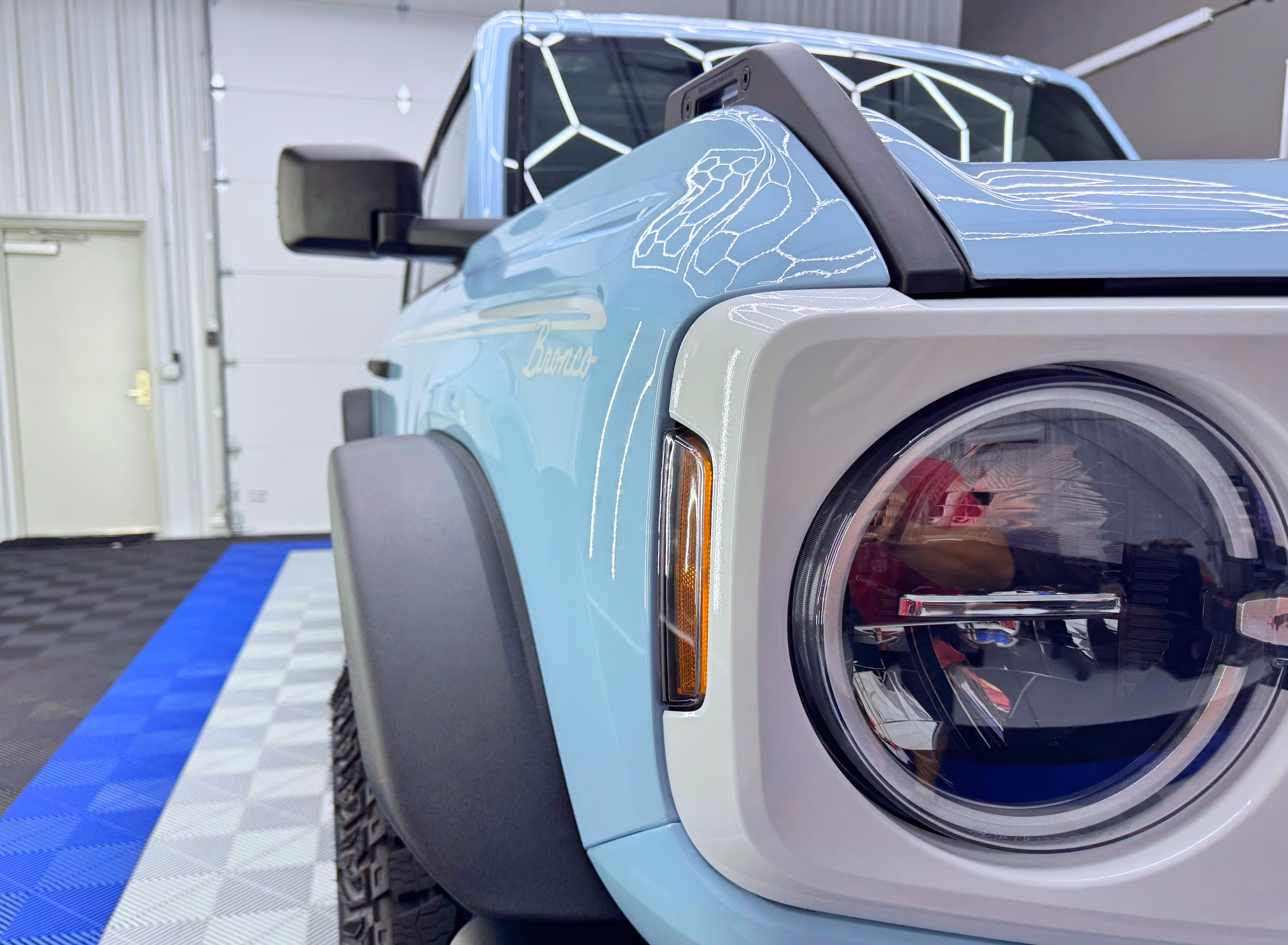 Light blue car headlight shining after paint protection film service in Chattanooga.