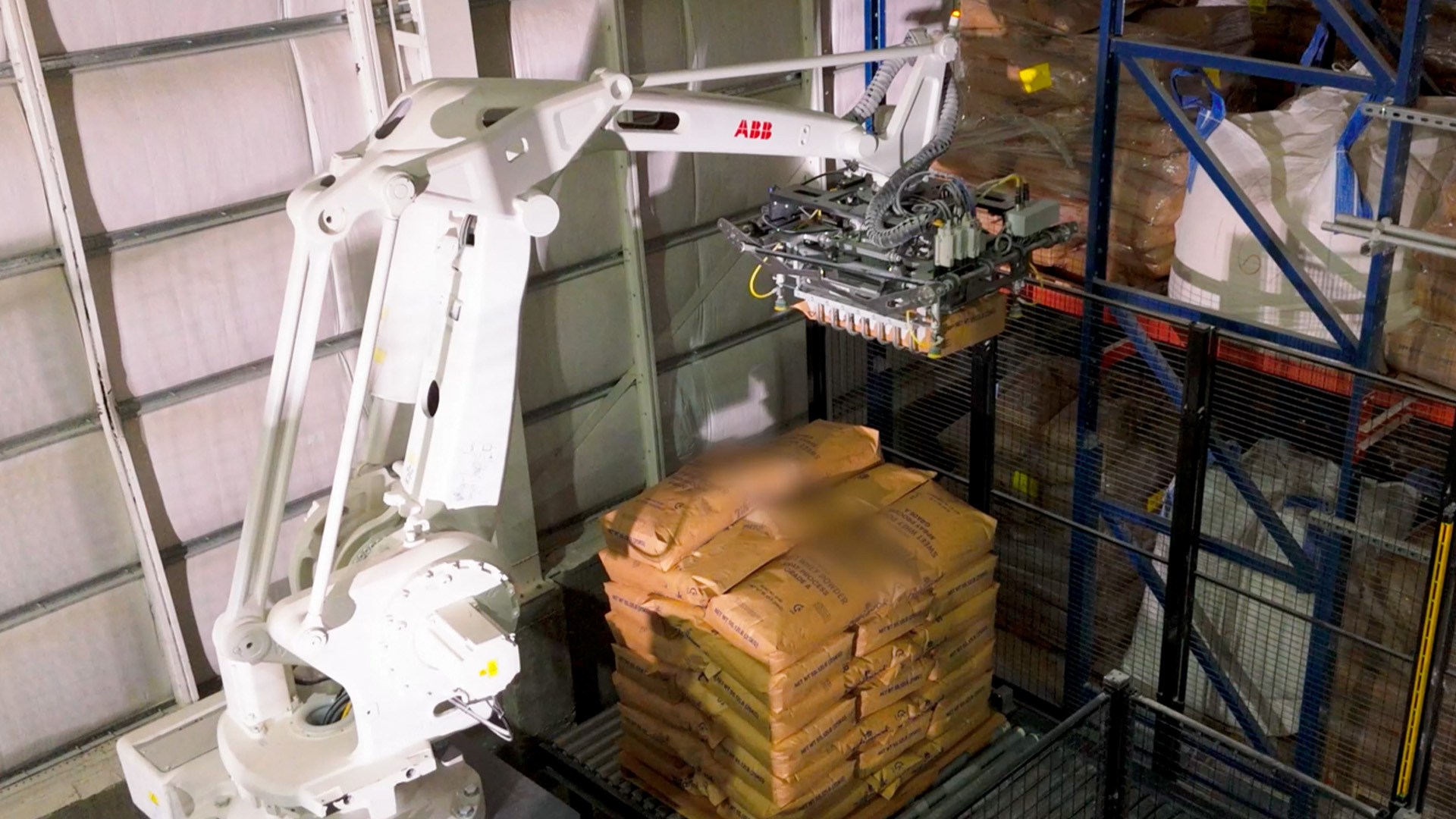 A robot arm stacking bags of whey on a pallet in a dairy processing facility