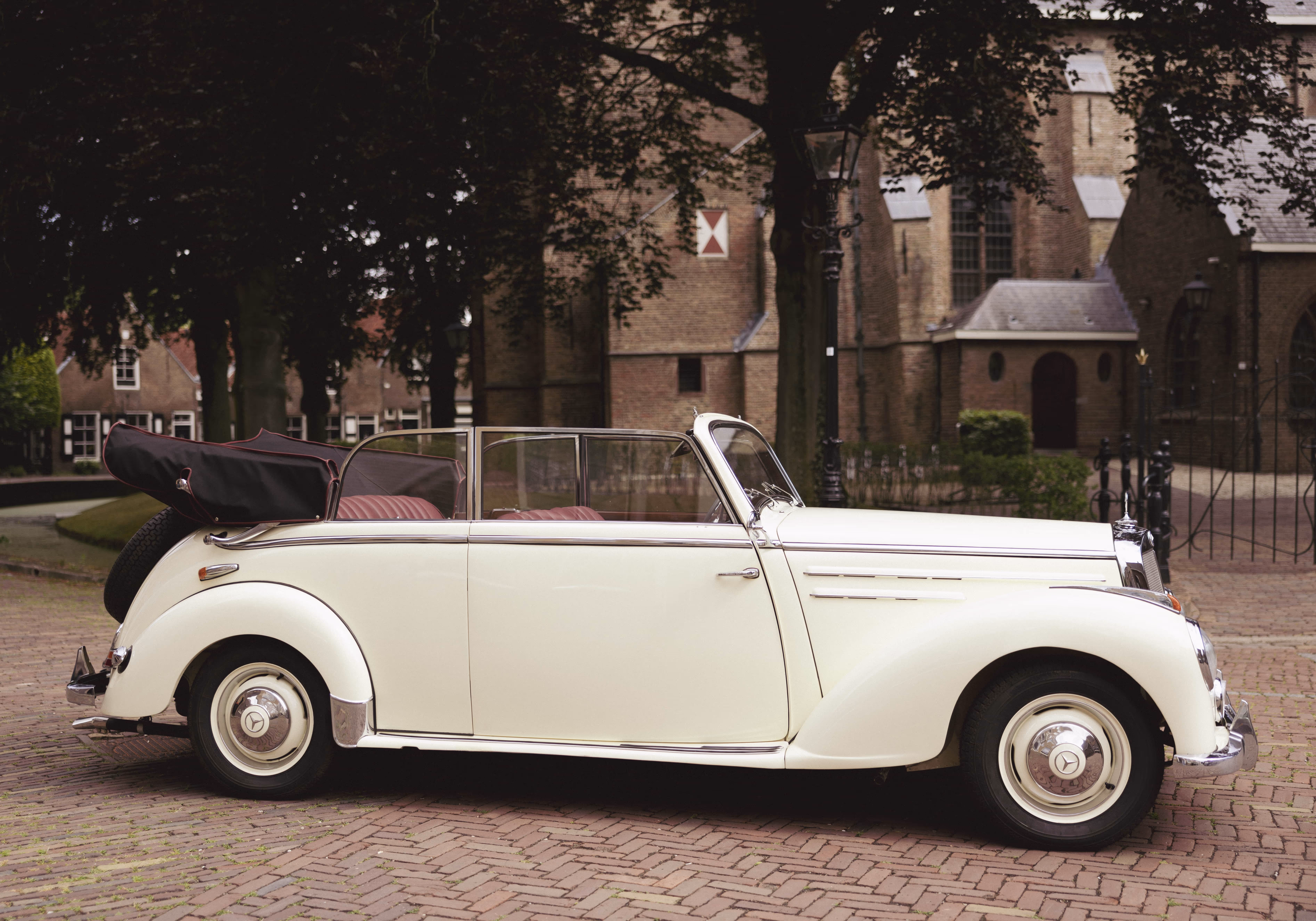 Klassieke witte borgo trouwauto geparkeerd voor een oude kerk