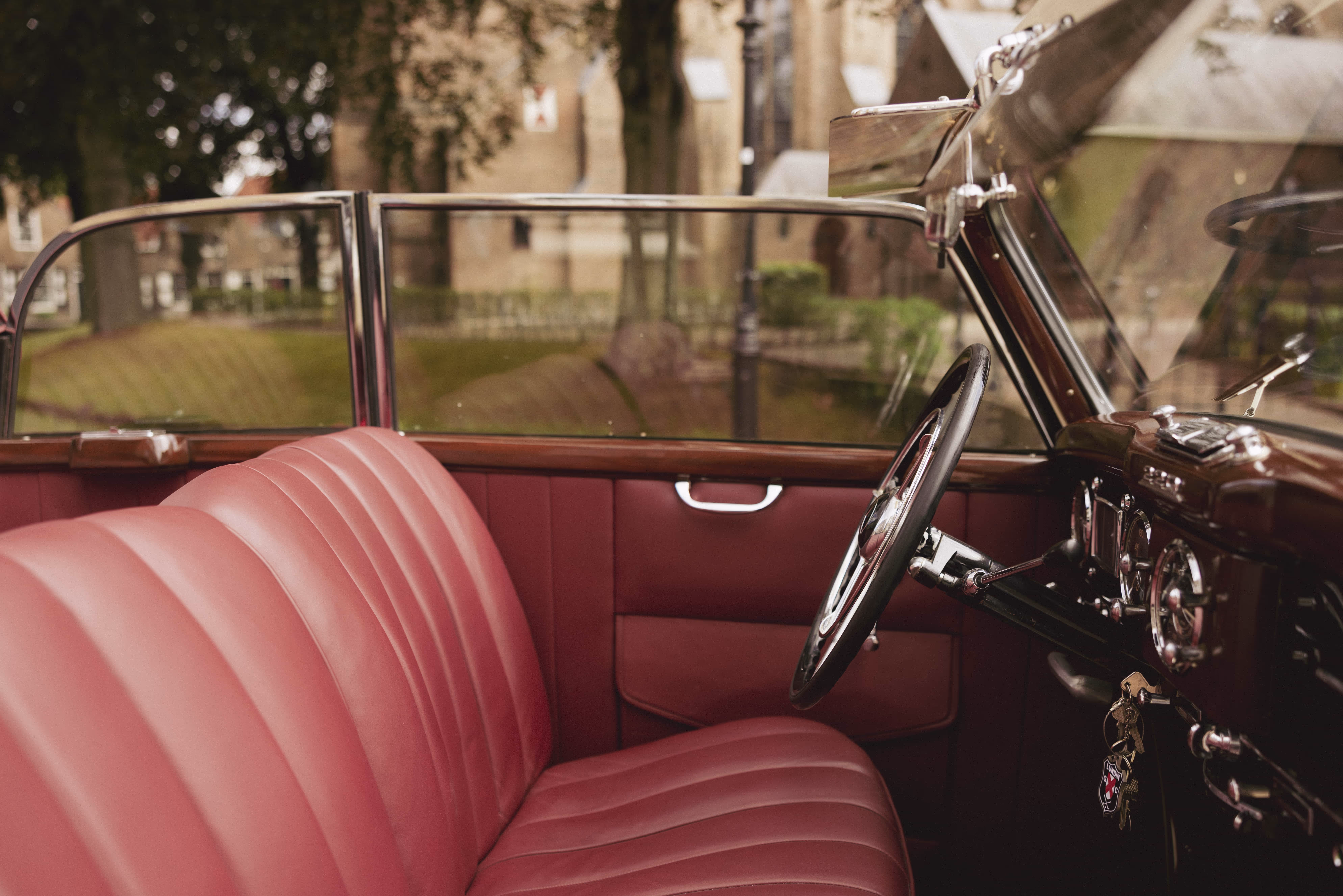Klassieke borgo trouwauto met rode leren stoelen en open dak