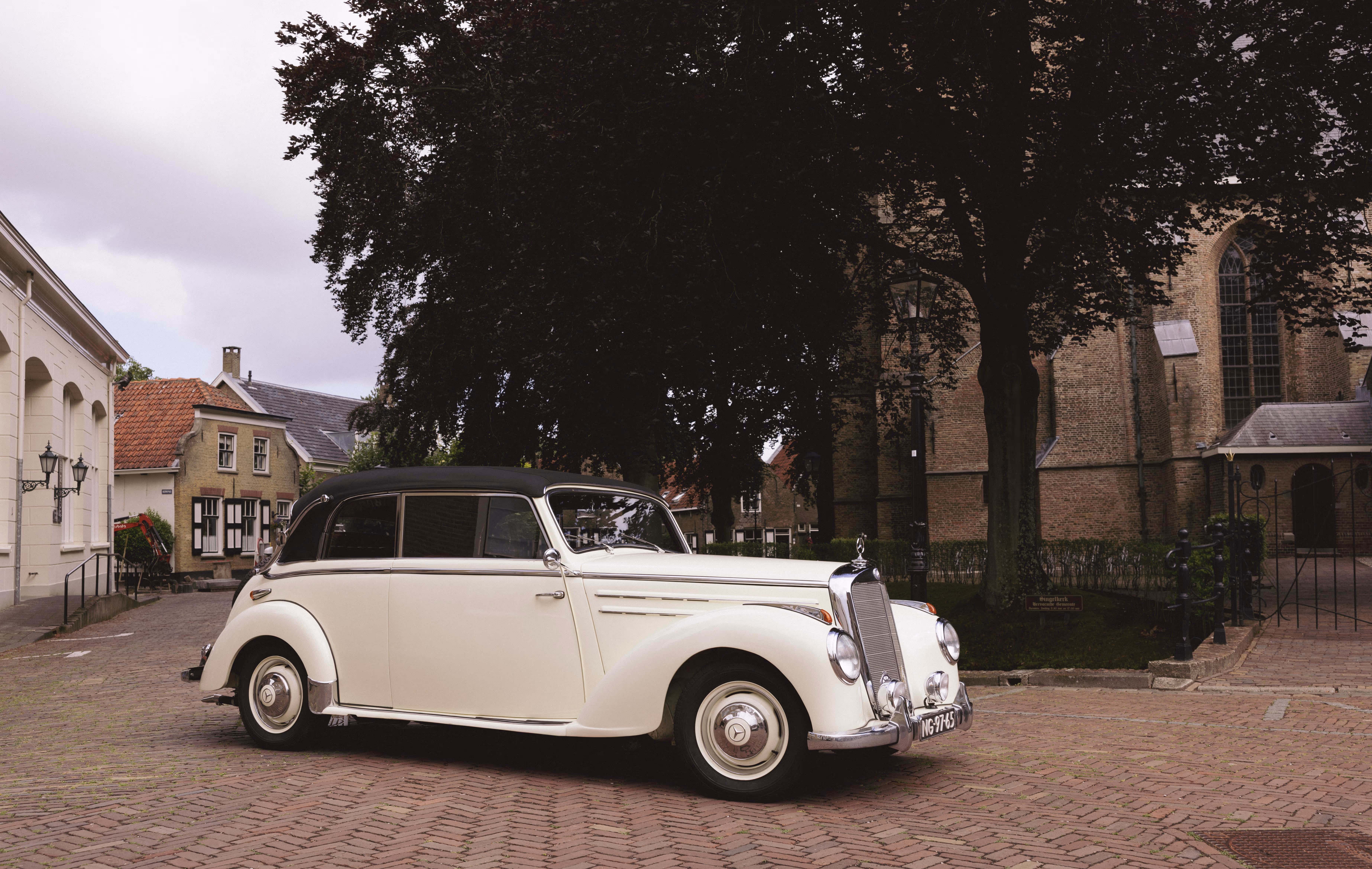 Klassieke witte trouwauto in een schilderachtig borgo met oude kerk