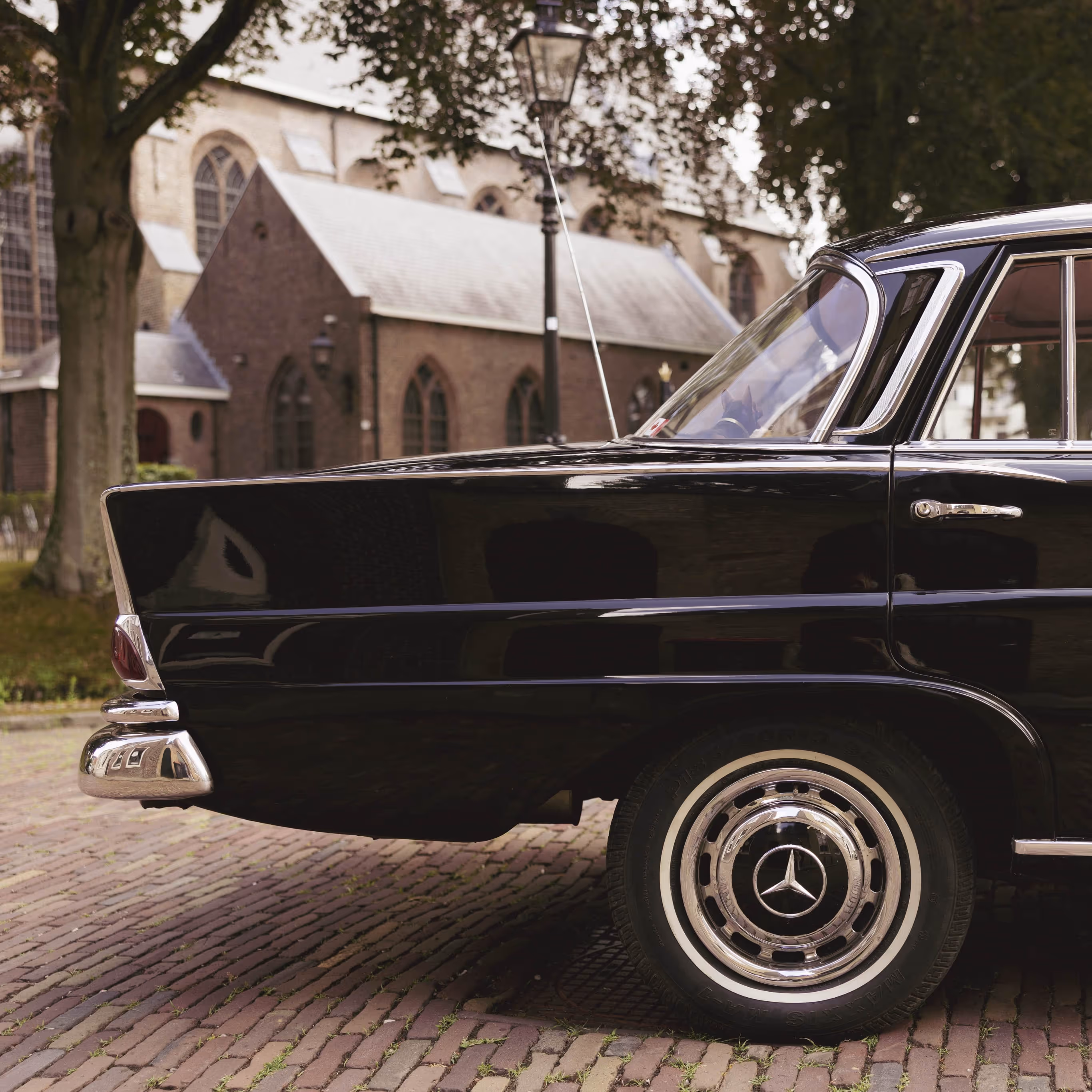 Klassieke borgo Mercedes trouwauto geparkeerd voor een oude kerk