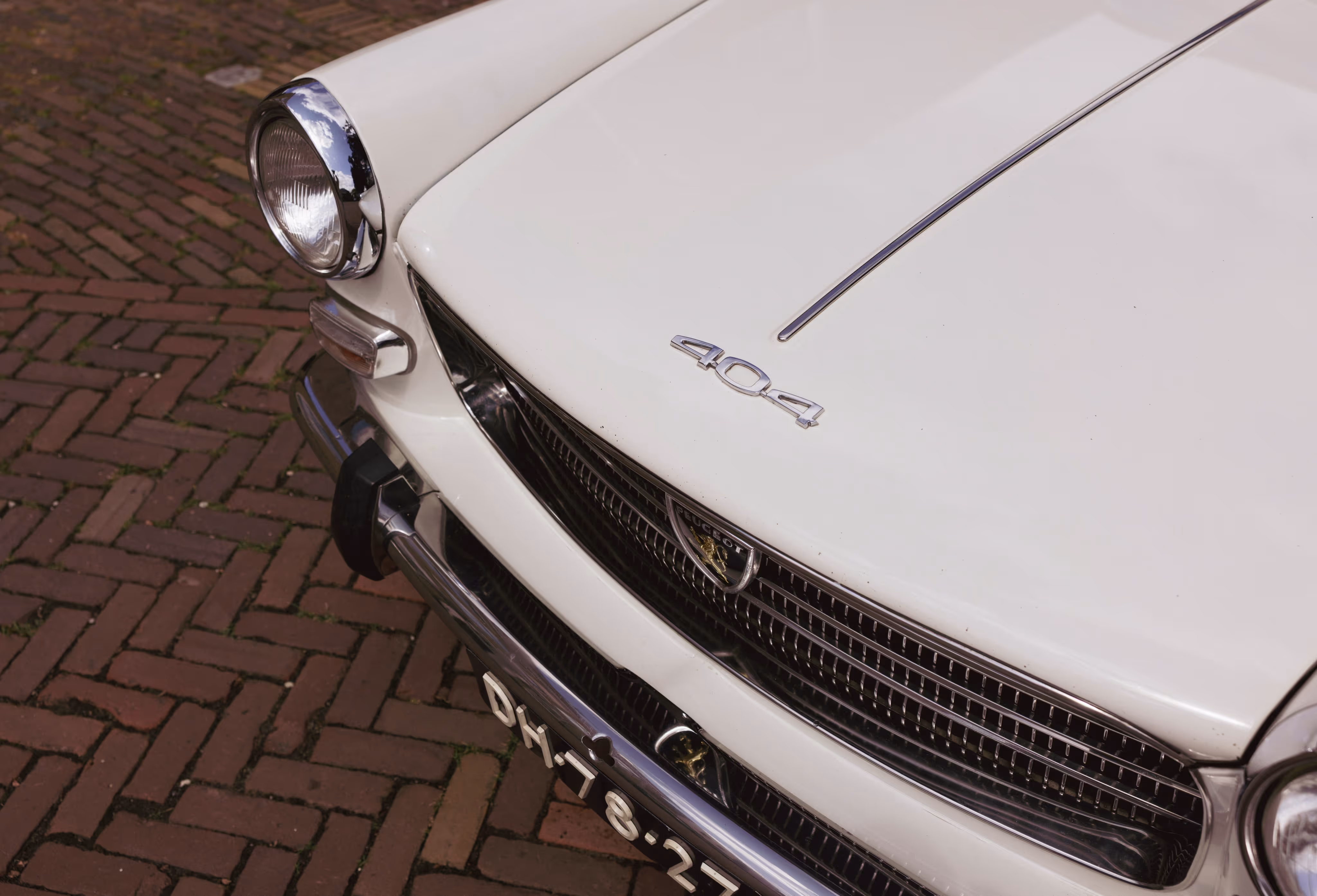 Borgo klassieke trouwauto, witte 404 met glanzende details op klinkerbestrating