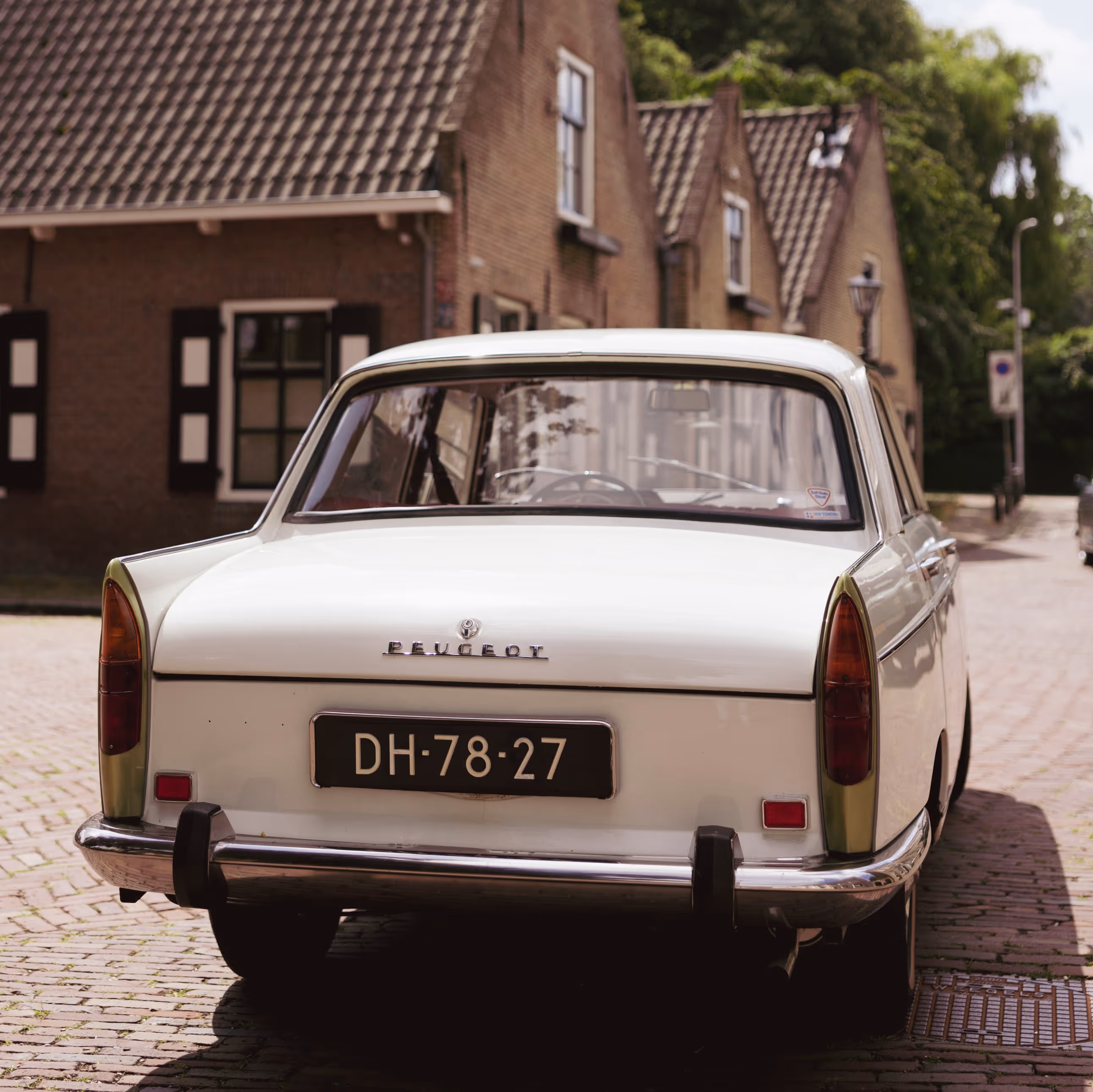 Klassieke witte Peugeot trouwauto in borgo met oude bakstenen huis
